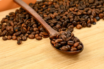 Coffee beans in wood spoon over the chop board