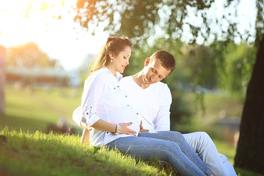 future parents sitting on the grass in the Park on a Sunny day.