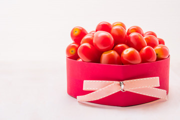 Red cherry tomatoes in gift box on white table background