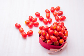 Red cherry tomatoes in gift box on white table background