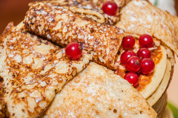 Rolled pancakes decorated with berries of red currant and and drizzled condensed milk while celebrating Russian Shrovetide (pancake week)