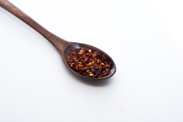 Chilli flakes in wooden spoon isolated