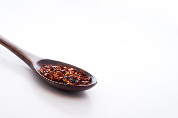 Chilli flakes in wooden spoon isolated