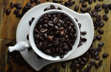 Coffee beans in white coffee cup with coffee beans scattered in background
