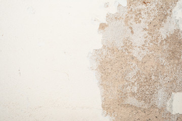 The texture of the old antique wall is white-gray-brown, part of the surface has a damaged layer of plaster, a porous part of the sand-lime base