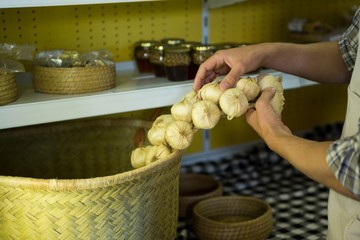 Mid-section of staff putting garlic in wicker basket