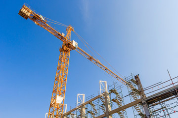 Fototapeta na wymiar Industrial construction cranes and building in a beautiful blue sky background