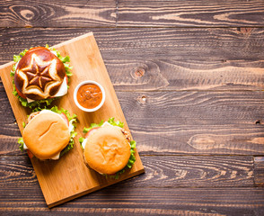 Top view of delicious hamburger, with vegetables,  on a wooden background.