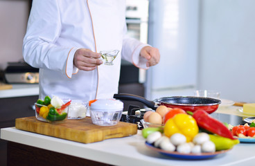 cook chef in kitchen and fresh vegetables on table