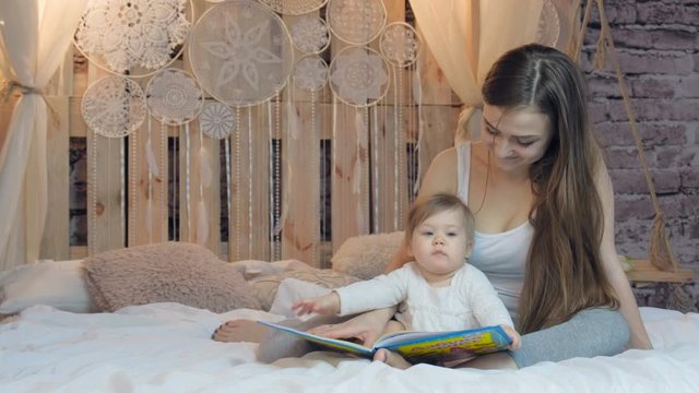 Mother and daughter reading a book together in bed