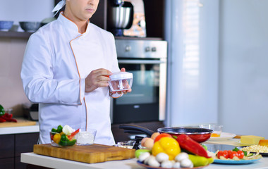 cook chef in kitchen and fresh vegetables on table