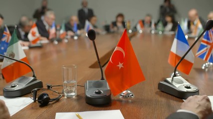 Turkish delegation at international summit or conference. Representatives of the Turkish government surrounded by other politicians give a speech at the round table. Audience applaud the speaker and