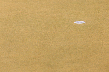 Selective focused on Golf hole on dried yellow grass of golf course.