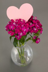 Close-up of flower vase with blank heart shape card