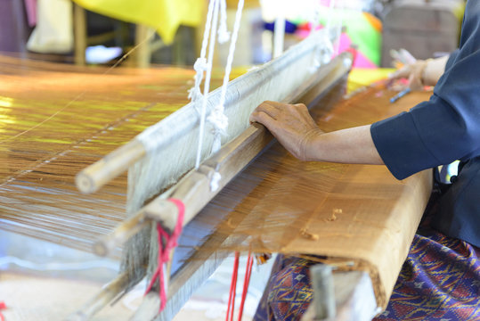 Close up of gold silk weaving on loom, cotton on the manual wood loom in Asian traditional culture and woman hand weave lifestyle