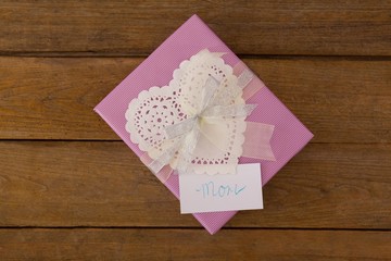 Gift box with mom text on card against wooden background