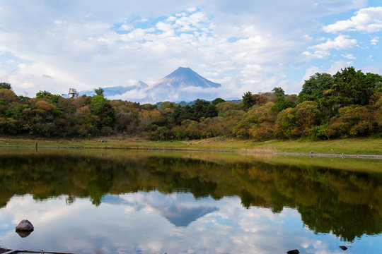 El volcán de Colima reflejado en el lago y con un cielo de muchas nubes.