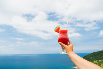 Fruit watermelon neck on an outstretched hand against the background of a tropical landscape. Relaxing holiday.