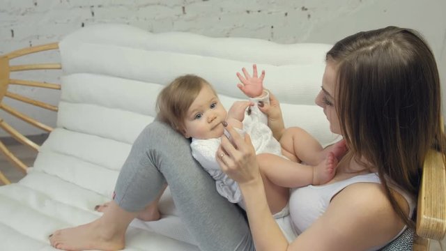 Happy Mother kissing Baby's feet with relax in a bedroom.
