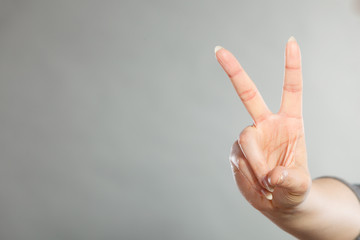 Female hand shows victory symbol.