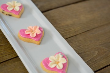 Heart shape cookies in tray on wooden plank