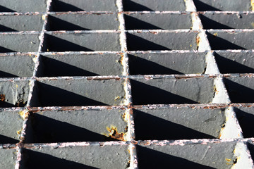 Steel grating drain cover, abstract light trait, triangle holes and light beams.