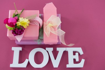 Gift boxes with flowers and text love against pink background
