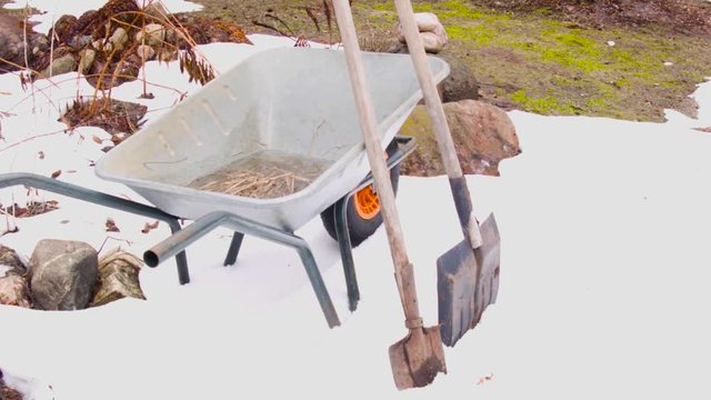 Abandoned gardening  trolley and shovels on the  melting snow