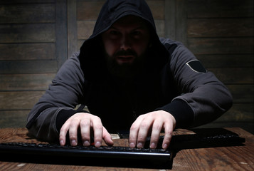 hacker in the black hood in a room with wooden walls