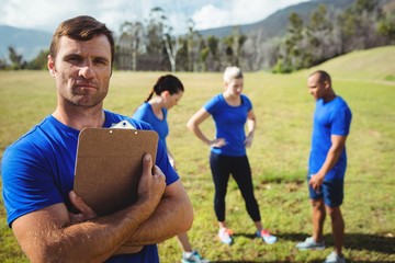 Fit man standing and holding a clipboard in boot camp