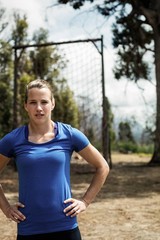 Portrait of woman standing with her hands on hip in boot camp