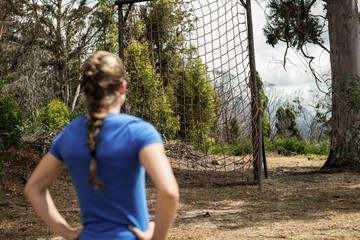 Rear view of woman standing with her hands on hip in boot camp