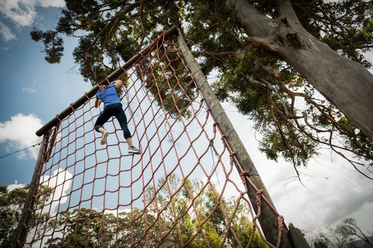 Woman climbing a net during obstacle course