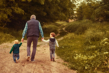 Naklejka na ściany i meble father walks with children in the Park