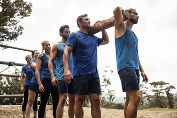 People carrying a heavy wooden log during boot camp