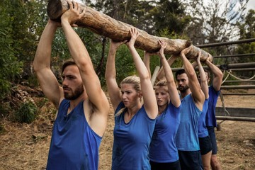 People lifting a heavy wooden log during boot camp
