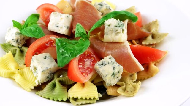 Close-up view of Farfalle bowtie pasta with blue cheese, Spanish Hamon, tomatoes and basil leaf
