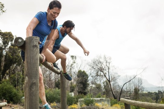 Couple jumping over the hurdles during obstacle course