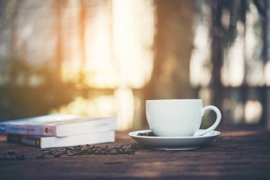 Cup of coffee with pile of books on natural morning background.