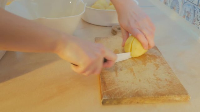 Female hands cut potatoes in the kitchen