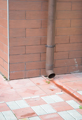 Rain Gutter Plastic Pipeline with Drainage Downspout System, Pavement near House Foundation.