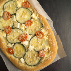 vegetable pizza, zucchini, cherry. on paper parchment.