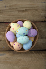 Overhead of Easter Eggs in Wicker Bowl Over Wooden Background