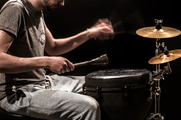 man playing a djembe drum and cymbals on a black background
