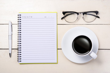 Fototapeta na wymiar White set. Pen, eyeglasses, coffee and notebook on table. Top view.