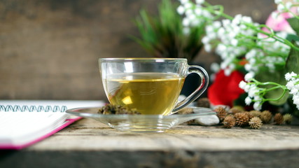 Hot tea in the morning. A Cup of tea on the wood desk with flowers background