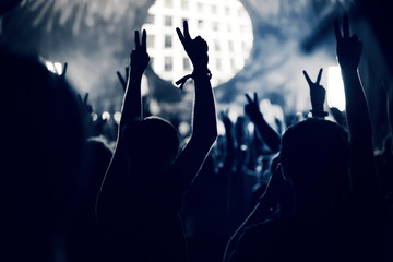 Crowd at a music concert, audience raising hands up, toned