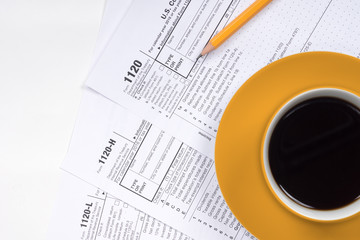 1120 tax forms top view with coffee cup and pencil