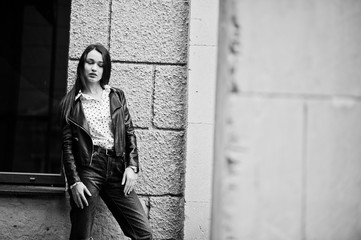 Portrait of stylish young girl wear on leather jacket and ripped jeans at streets of city. Street fashion model style. Black and white photo.