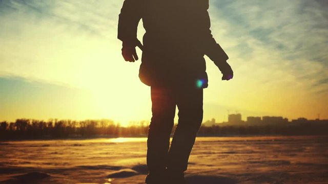 Silhouette of young man rises hands on mountains in winter sunny day on urban background with sunshine and lense flare effects in slow motion. 1920x1080